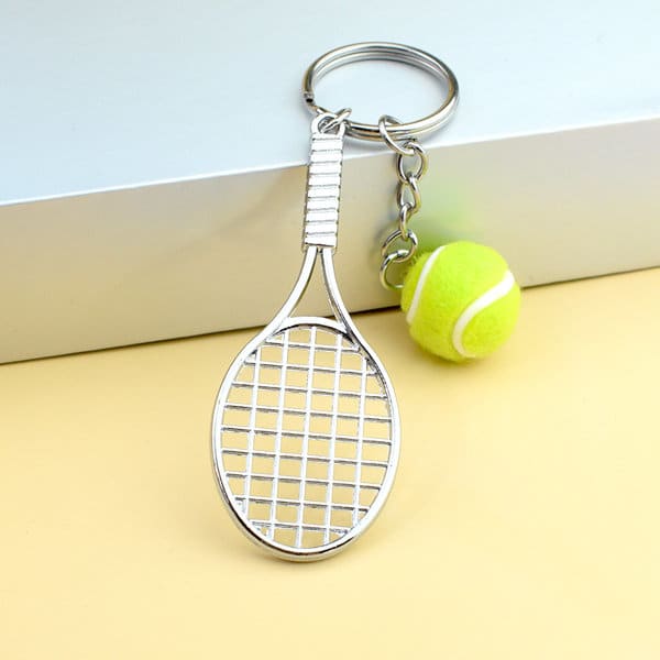 A key ring featuring a silver tennis racket design and a small green tennis ball charm. Tennis Ball And Racket Key Ring - Image 1