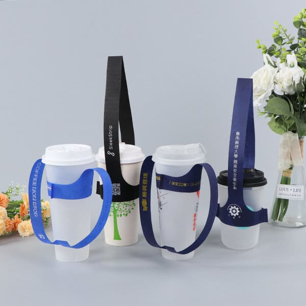 A set of four disposable T-type handle cup carriers in blue and black, with varying strap designs, alongside a floral arrangement. Disposable T-type Handle Cup Carrier - Image 1