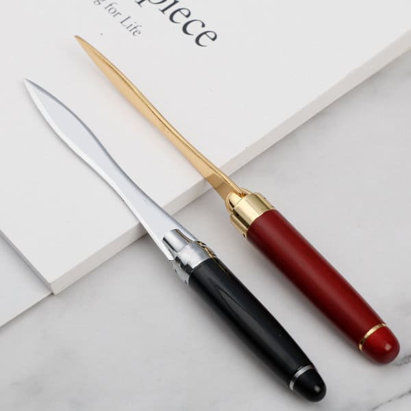 A wood handle letter opener featuring a black handle with a silver blade and a red handle with a gold blade, resting on paper. Wood Handle Letter Opener - Image 1
