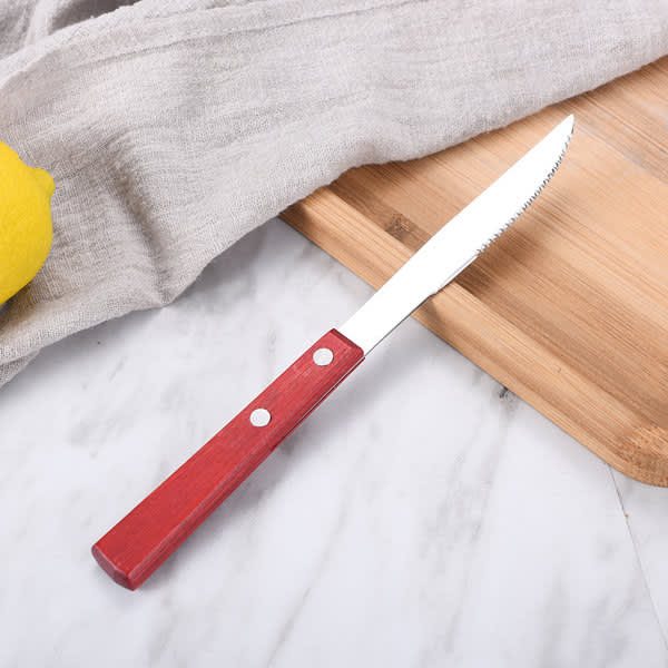 A steak knife with a red wooden handle rests on a cutting board, accompanied by a grey cloth and a lemon. Steak Knife And Dinner Forks Set - Image 1