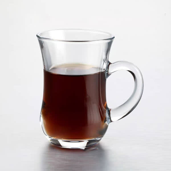 A transparent tea cup with a curved handle filled with dark liquid. The cup is made of glass and has a sleek design. Transparent Tea Cup - Image 1