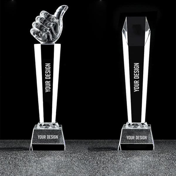 A crystal thumbs up trophy featuring a clear thumb design atop a rectangular base, with a black section for custom engraving. Engraved Crystal Thumbs Up Trophy - Image 1