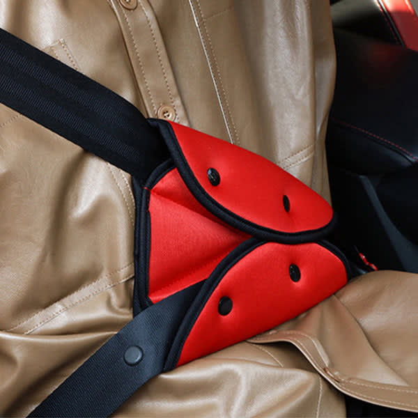 A kids car seat belt adjuster in red and black fabric, featuring buttons, placed on a car seat. Kids Car Seat Belt Adjuster - Image 1