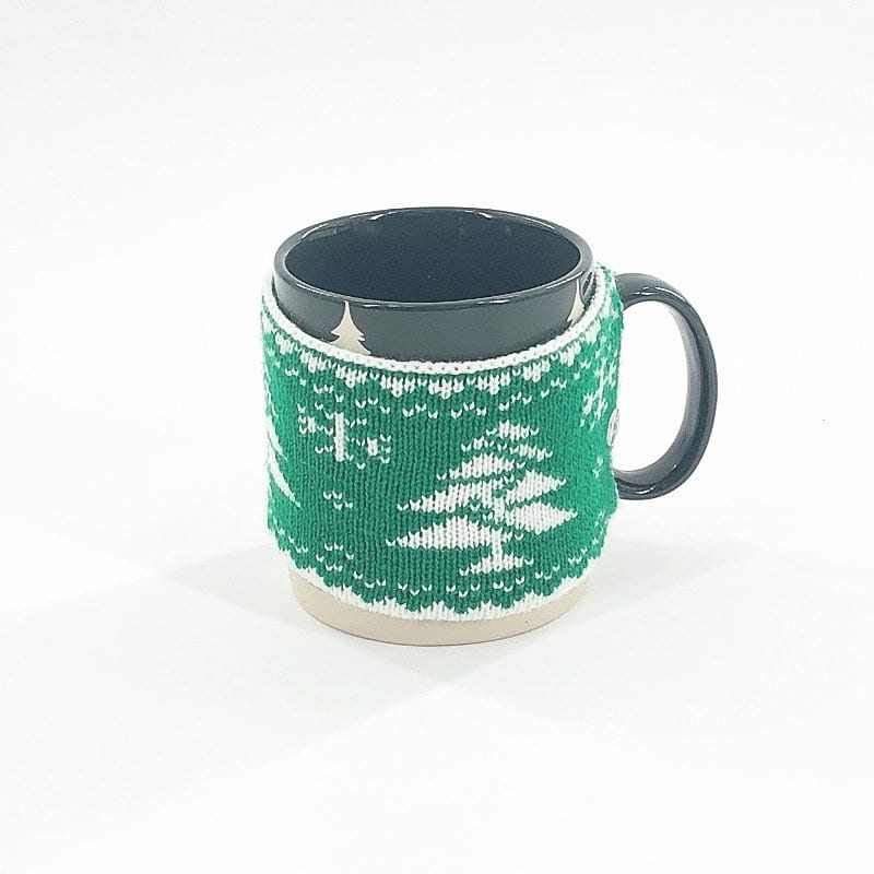 A black coffee mug with a green knitted cup sleeve featuring a winter design. The sleeve is decorated with white patterns. Christmas Mug Knitted Cup Sleeve - Image 1