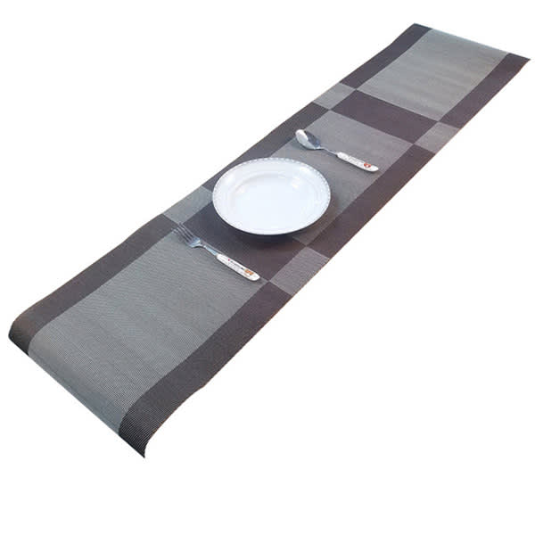 A grey and black woven placemat featuring a checkered pattern, with a plate and cutlery arranged on it. Promotional PVC Woven Placemat - Image 1