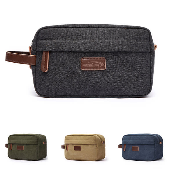 A toiletry bag in dark grey with a brown handle and logo, with additional bags in olive green, tan, and blue. Canvas Travel Cosmetic Shaving With Handle - Image 1