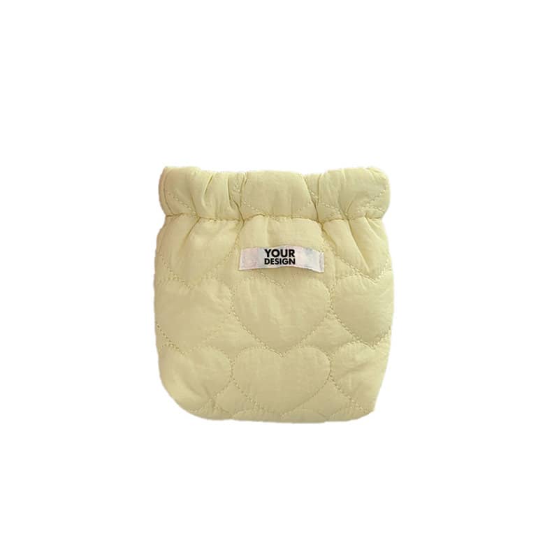 A quilted cosmetic bag in soft yellow with a heart pattern and a label for custom design. Compact Cotton Cosmetic Bag - Image 1