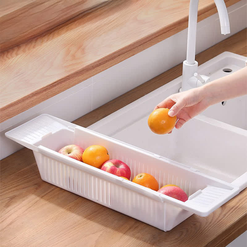 A white rectangular sink basket holding various fruits including apples and oranges, positioned next to a sink. Multifunctional Bathroom Bathtub Tray - Image 1