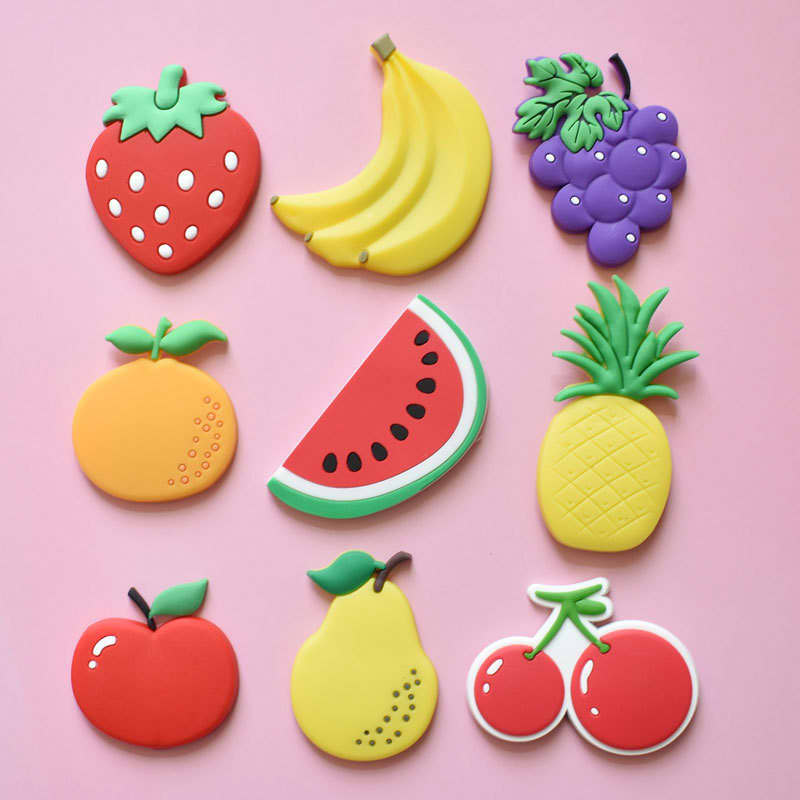 A collection of colourful fruit-shaped fridge magnets, including strawberries, bananas, grapes, watermelon, and others on a pink background. Custom Frigerator Magnet - Image 1