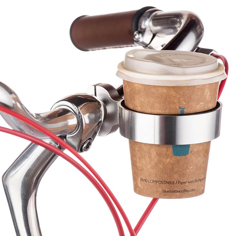 A drink bottle holder in silver, attached to a bike handlebar, holding a coffee cup wrapped in a cardboard sleeve. Bike Drink Coffee Bottle Holder - Image 1
