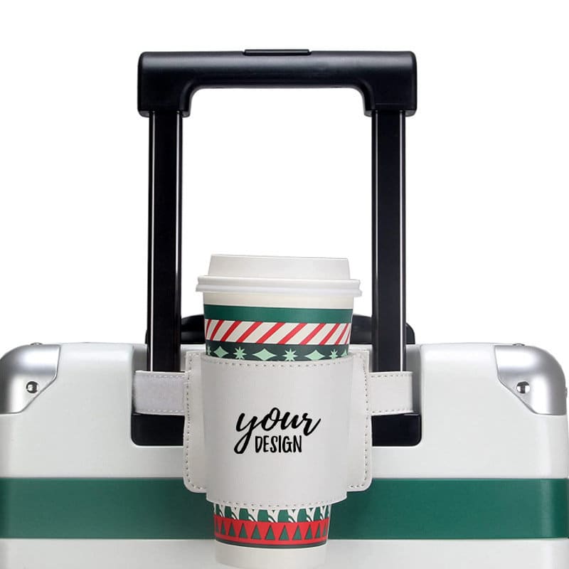 A drink bottle holder with a coffee cup sits on a wheeled bag, featuring a green and white design. Luggage Handle Cup Holder - Image 1
